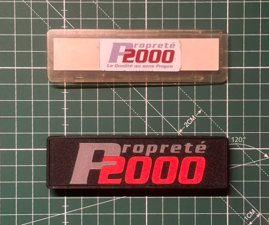 Une plaque d'origine et sa reproduction imprimée en couleurs, posées sur un tapis de découpe gradué