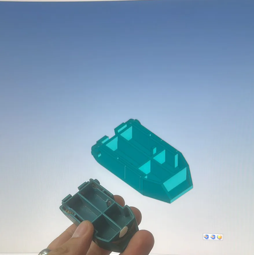 Une pièce cassée tenue devant l'écran où sa copie est modélisée en 3D